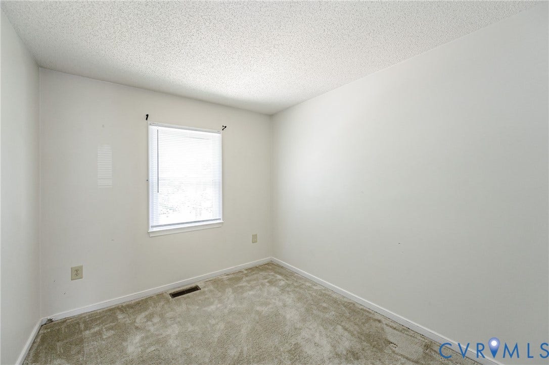Carpeted room with a single window featuring horizontal blinds