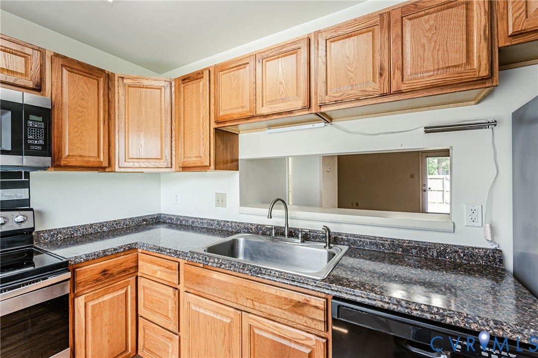 Kitchen featuring wood cabinetry, speckled countertops, stainless steel sink with a gooseneck faucet, black dishwasher, and built-in microwave