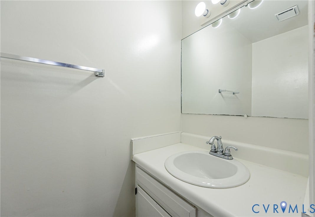 Bathroom vanity with an integrated sink, chrome faucet, and a large wall-mounted mirror