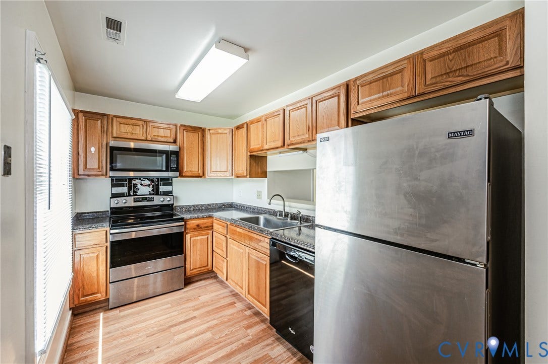 Kitchen featuring wood-finish cabinetry, stainless steel appliances, laminate countertops, and wood-finish flooring
