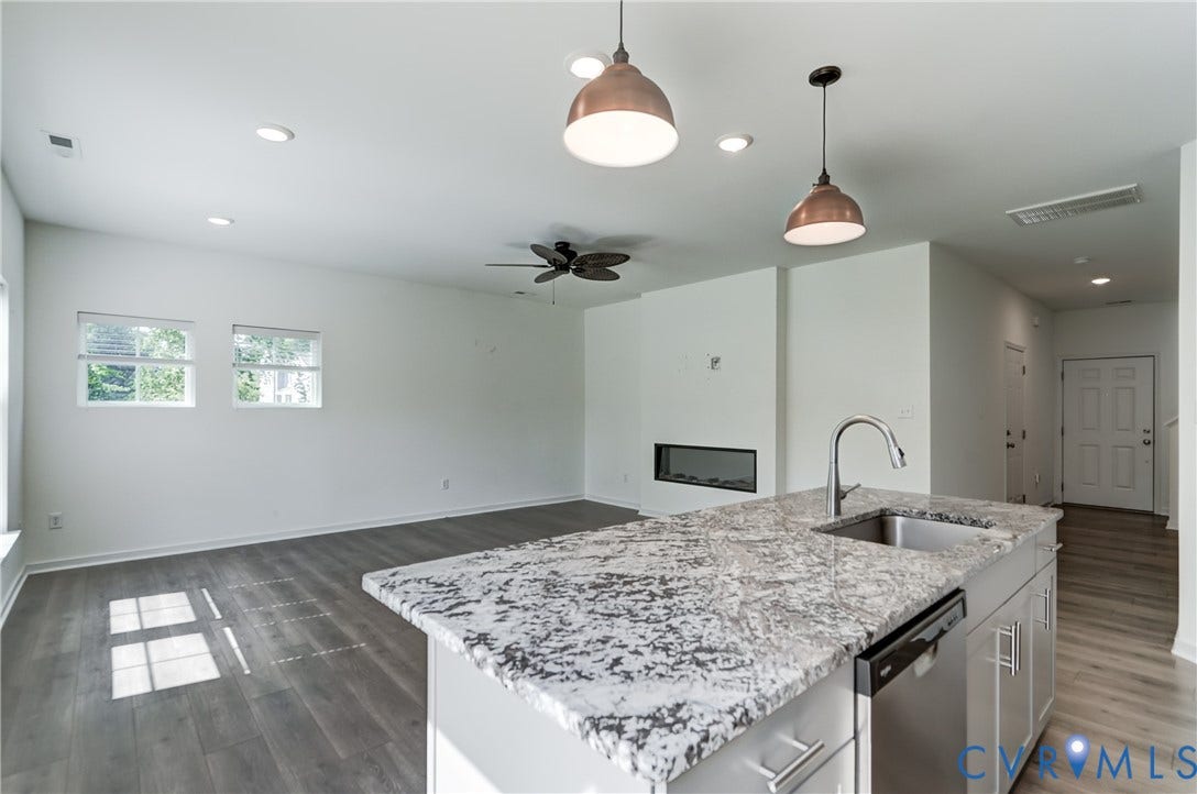 Kitchen island with a stainless steel sink and faucet, integrated dishwasher, and light-toned countertop
