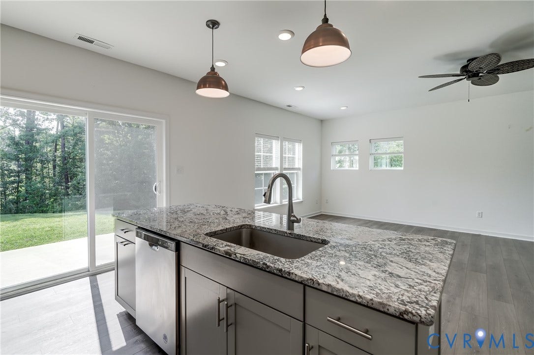Kitchen island featuring a stainless steel sink, gooseneck faucet, and granite countertop