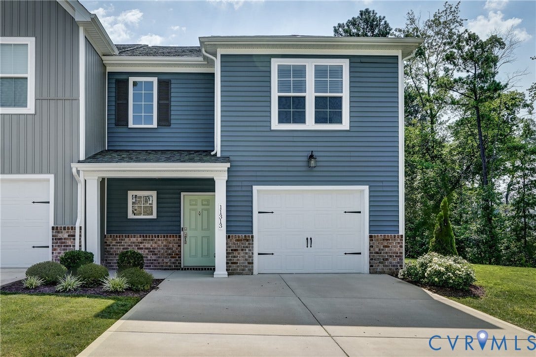 Modern townhome facade featuring blue siding, white trim, and a brick foundation
