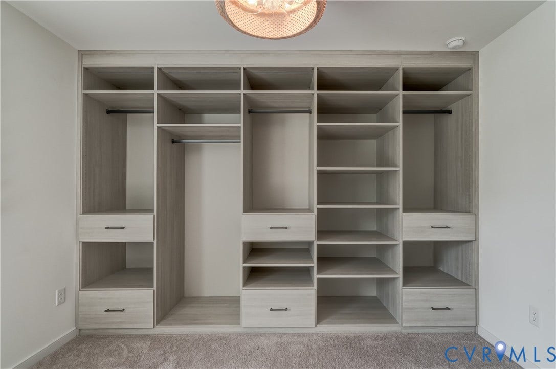Built-in closet system featuring a light wood-finish with multiple shelving units, integrated drawers, and hanging rods