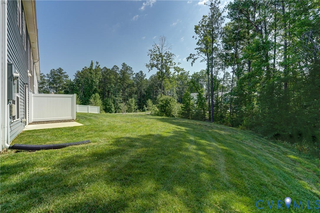 Expansive green lawn with a white privacy fence