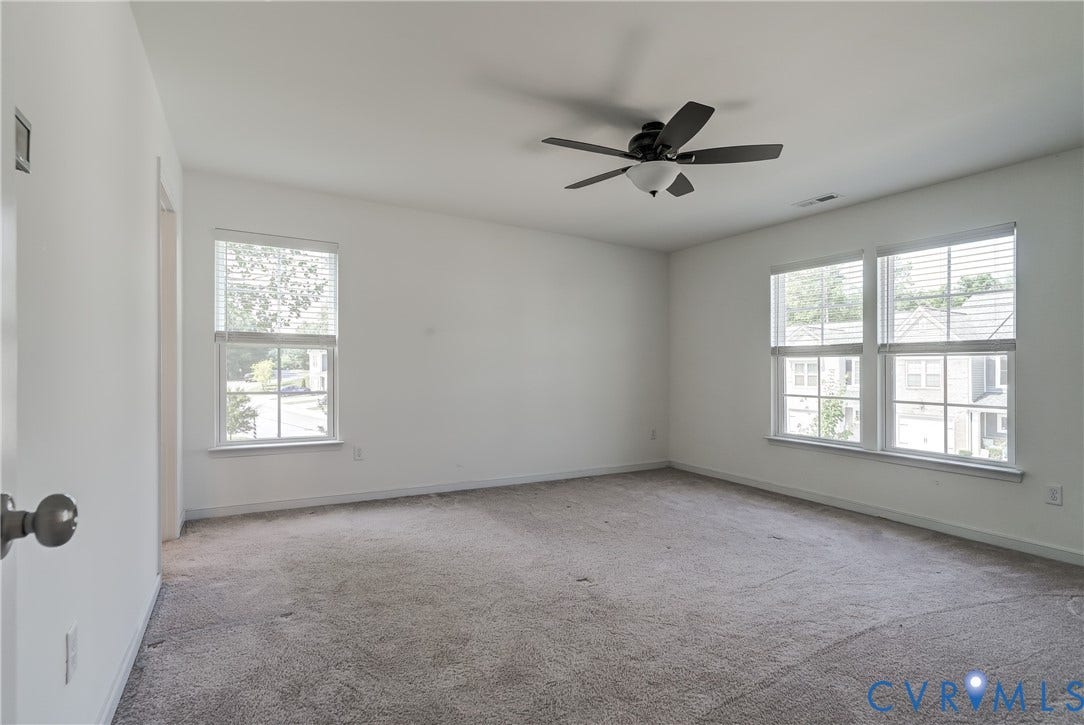 Spacious room featuring neutral carpet flooring, white walls, and a contemporary ceiling fan with integrated lighting