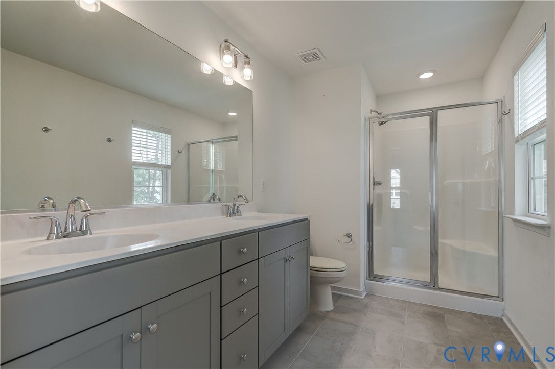 Bathroom featuring a dual vanity with gray cabinetry, white countertops, and chrome fixtures