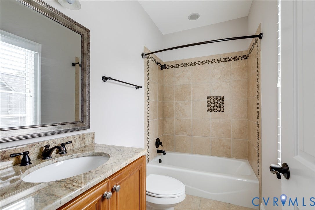 1978 Farnborough Drive, Midlothian, VA 23112 Bathroom featuring a warm wood-finish vanity with a light-toned countertop, an oval undermount sink, and dark bronze fixtures