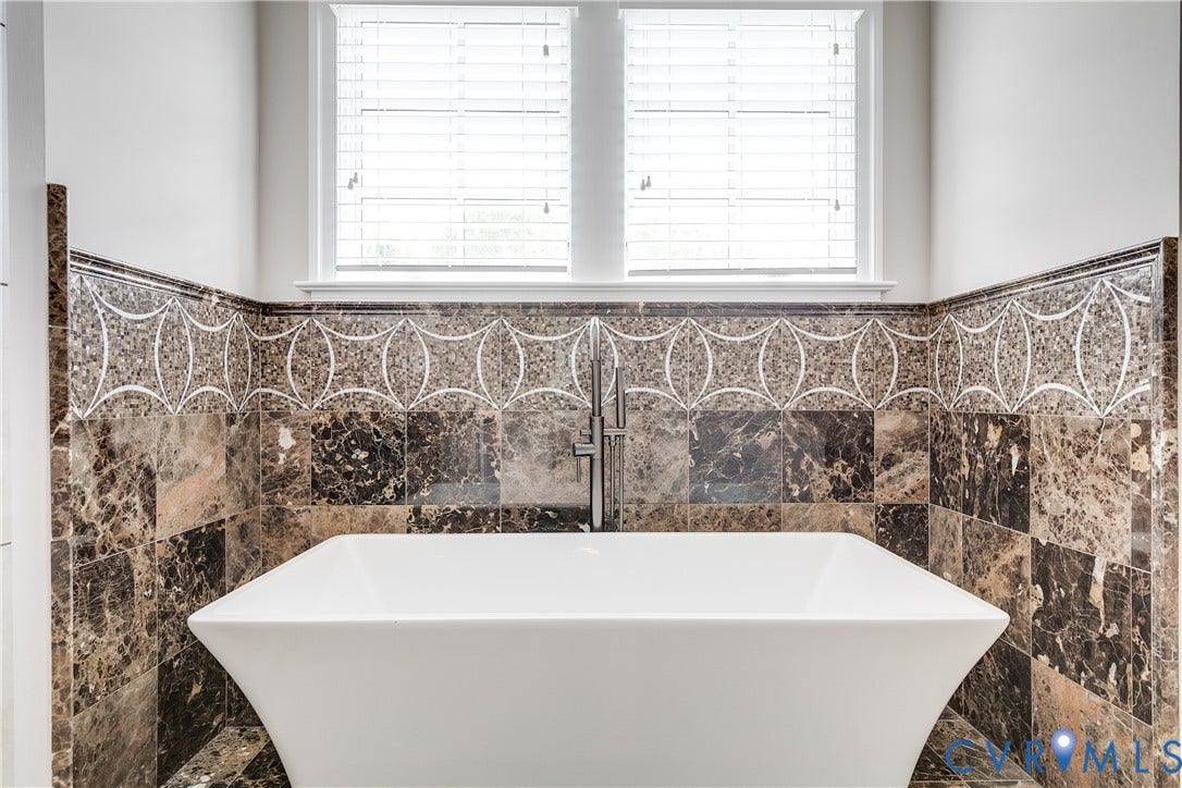 1978 Farnborough Drive, Midlothian, VA 23112 Freestanding soaking tub with a floor-mounted faucet set against a wall featuring decorative mosaic tile work