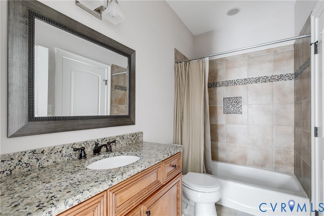 1978 Farnborough Drive, Midlothian, VA 23112 Bathroom featuring a wood-finish vanity with a speckled countertop, an undermount sink, and a decorative framed mirror