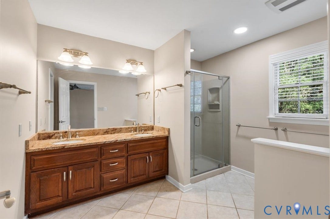 1437 Palmore Road, Powhatan, VA 23139 Bathroom featuring a double vanity with a stone countertop, dual undermount sinks, and a framed glass shower enclosure