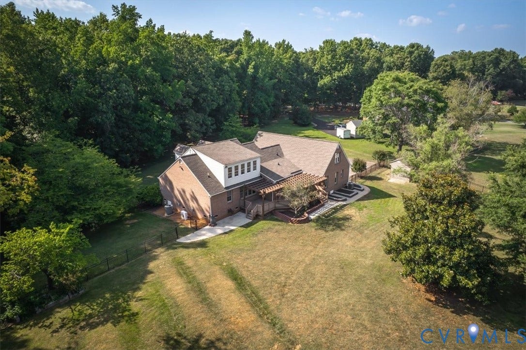 1437 Palmore Road, Powhatan, VA 23139 Brick residence featuring a dormer with multiple windows, a rear deck with a pergola, and a concrete patio
