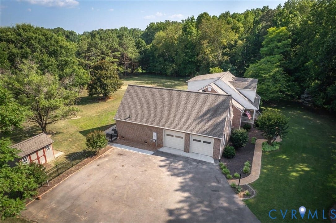 1437 Palmore Road, Powhatan, VA 23139 Brick home featuring a two-car garage, paved driveway, landscaped walkway, and a separate storage shed