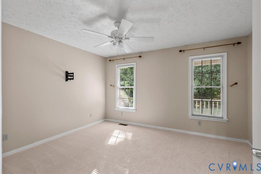 1437 Palmore Road, Powhatan, VA 23139 Carpeted room featuring a ceiling fan, two double-hung windows with white trim, and a wall-mounted bracket