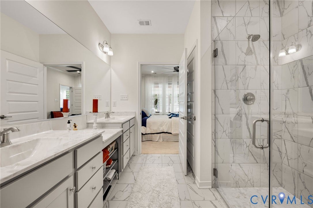 9217 Cerulean Place, Goochland, VA 23238 Spacious bathroom featuring a glass-enclosed shower with white marble-look tile, double vanity with integrated sinks, and ample under-counter storage
