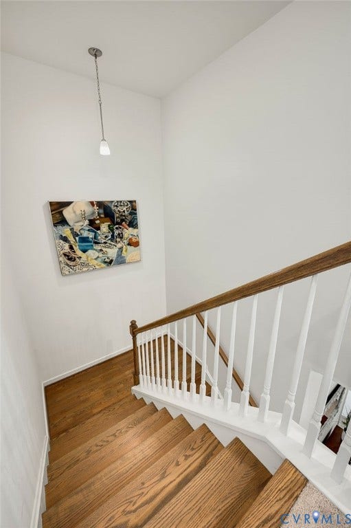 9217 Cerulean Place, Goochland, VA 23238 Staircase featuring wood-finish treads, a white spindle railing with a wood-finish handrail, and a pendant light fixture