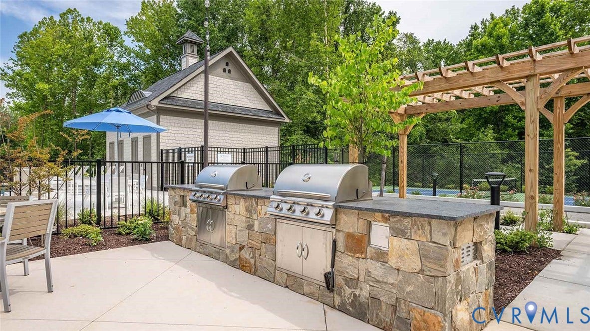 9217 Cerulean Place, Goochland, VA 23238 Outdoor kitchen featuring a stone veneer base with integrated stainless steel grills and a dark countertop