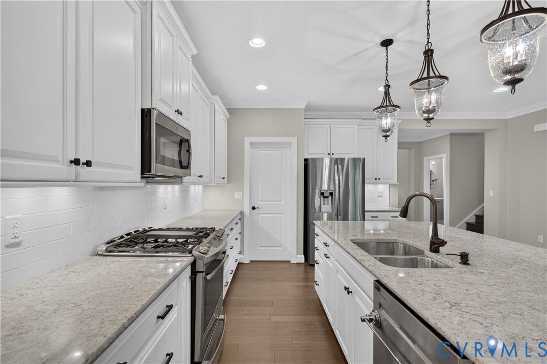 7238 Shenfield Avenue, Minutes To Short Pump, Glen Allen, VA 23059 Kitchen featuring white shaker-style cabinetry, stainless steel appliances, light-toned countertops, a subway tile backsplash, and wood-finish flooring