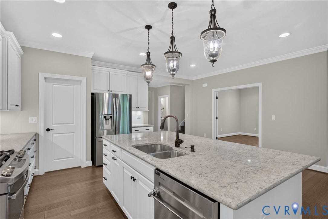 7238 Shenfield Avenue, Minutes To Short Pump, Glen Allen, VA 23059 Kitchen featuring an oversized island with double basin sink, stainless steel appliances, abundant white cabinetry, and wood-finish flooring