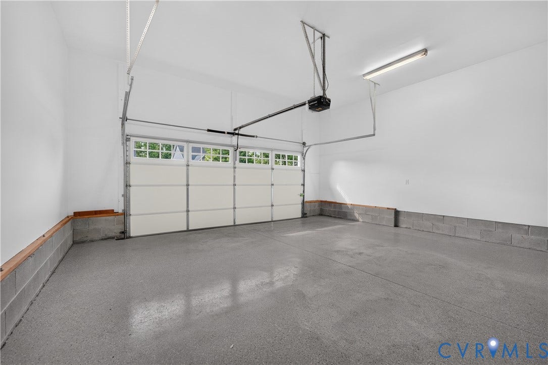 7238 Shenfield Avenue, Minutes To Short Pump, Glen Allen, VA 23059 Garage featuring an epoxy-coated concrete floor, painted concrete block walls, overhead fluorescent lighting, and a white paneled garage door with upper window inserts