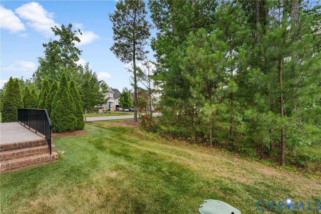 7238 Shenfield Avenue, Minutes To Short Pump, Glen Allen, VA 23059 Expansive lawn area with a brick foundation and concrete steps featuring a black metal railing