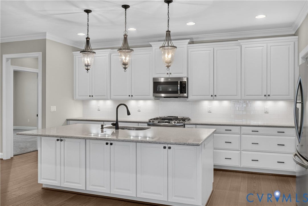 7238 Shenfield Avenue, Minutes To Short Pump, Glen Allen, VA 23059 Kitchen featuring white shaker cabinetry, an expansive center island with an undermount sink, pendant lighting, hardwood flooring, and stainless steel appliances