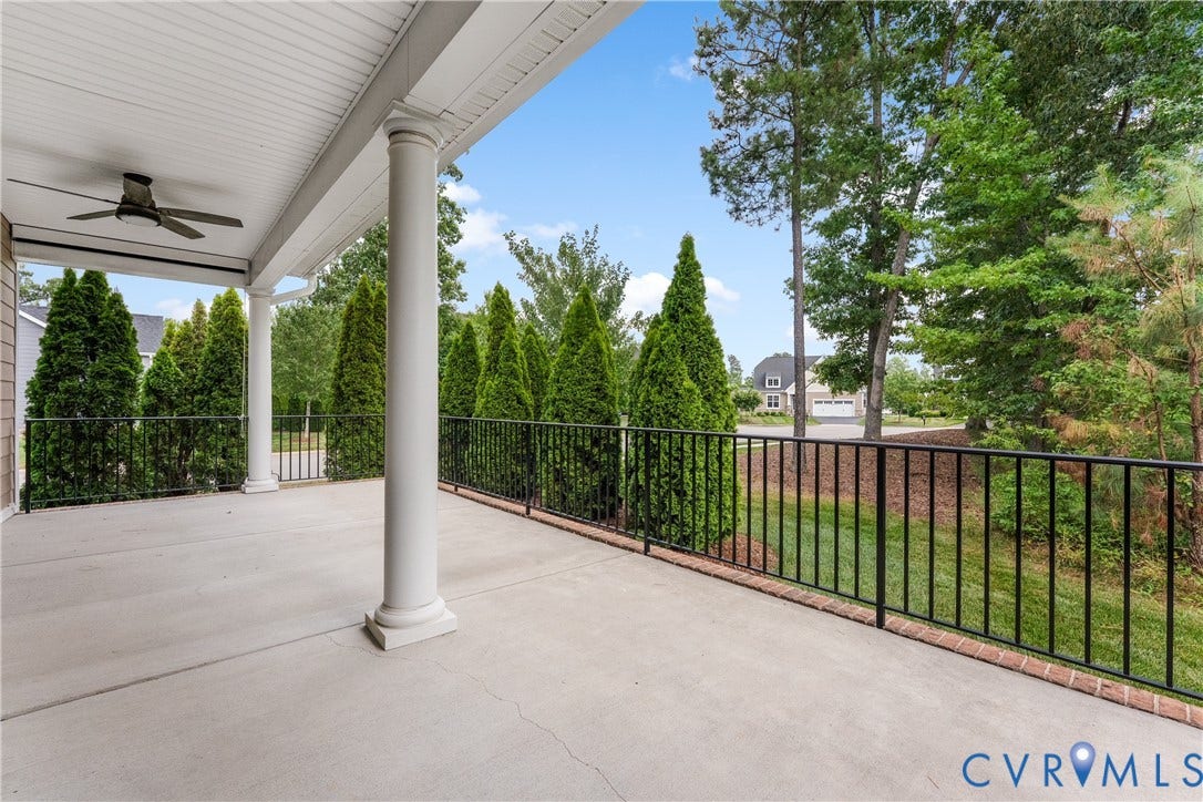 7238 Shenfield Avenue, Minutes To Short Pump, Glen Allen, VA 23059 Spacious concrete patio featuring a ceiling fan, white architectural columns, black iron railings, and mature evergreen privacy trees