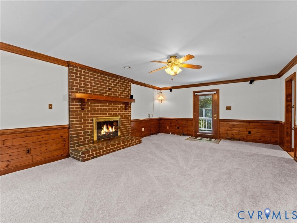 Brick fireplace with a wood mantel and hearth, complemented by a ceiling fan with integrated lighting
