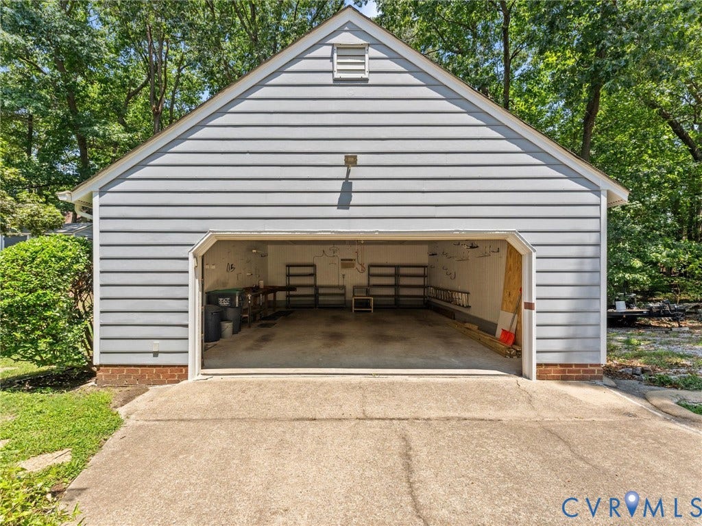 Detached garage with horizontal siding, a gable roof, and an overhead door opening