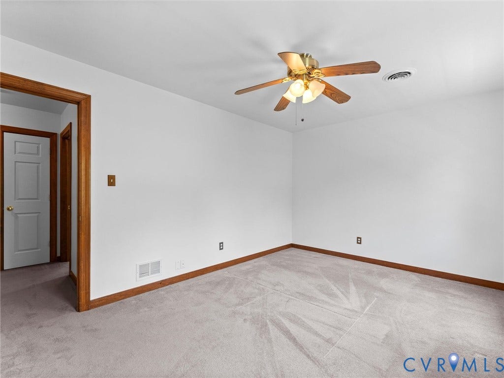 Bright room featuring a ceiling fan with integrated lighting, wood-finish trim, and light-toned wall-to-wall carpeting