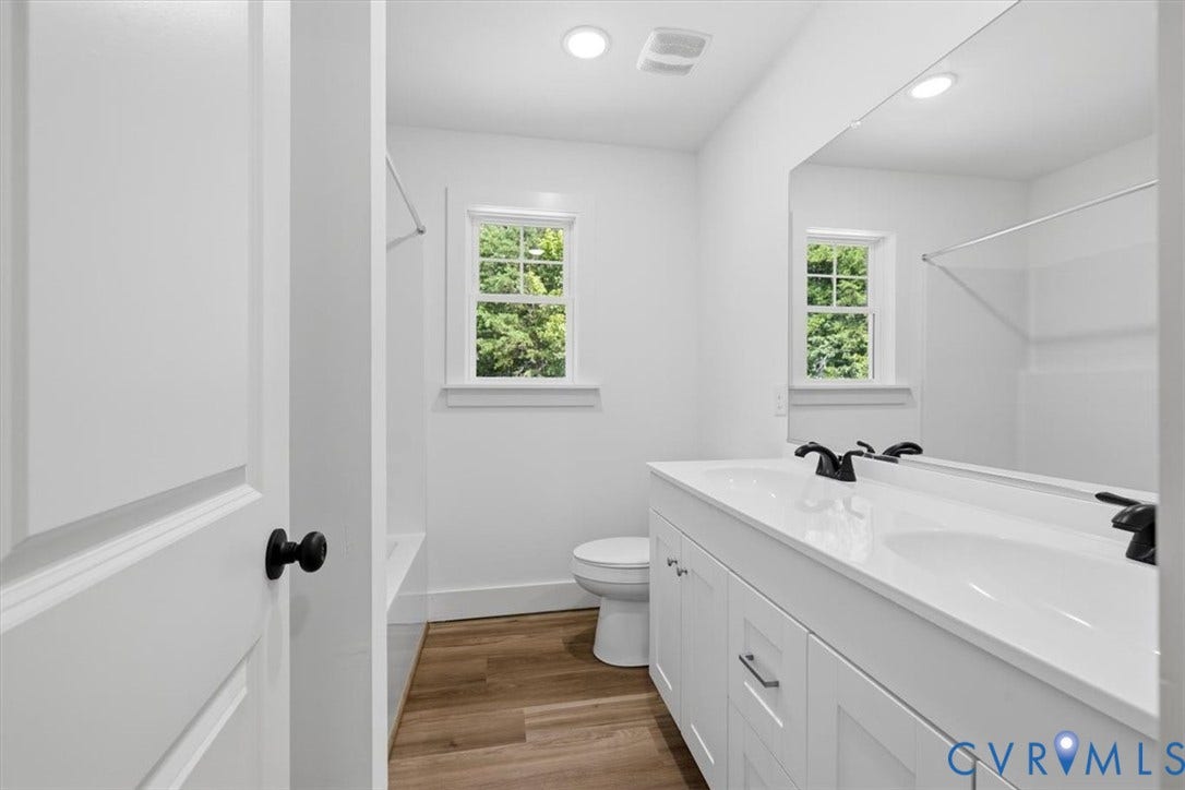 654 Frenchs Store Road, Cumberland, VA 23040 Bathroom featuring a dual vanity with white cabinetry and integrated sinks, matte black faucets, and an expansive wall-mounted mirror