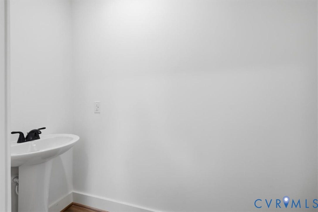 654 Frenchs Store Road, Cumberland, VA 23040 White pedestal sink with a matte black faucet set against a clean white wall and wood-finish flooring