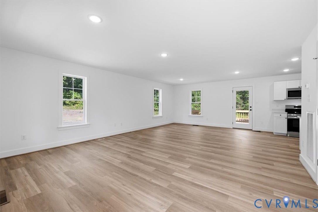 654 Frenchs Store Road, Cumberland, VA 23040 Open-concept room featuring wood-finish flooring, recessed lighting, multiple windows, and a rear door opening to a deck