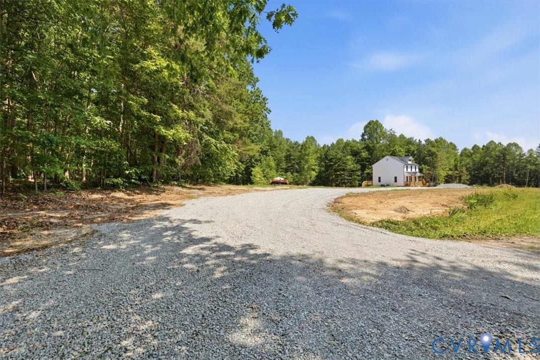 654 Frenchs Store Road, Cumberland, VA 23040 Gravel driveway approaching a two-story home with a light-colored exterior and a covered front porch