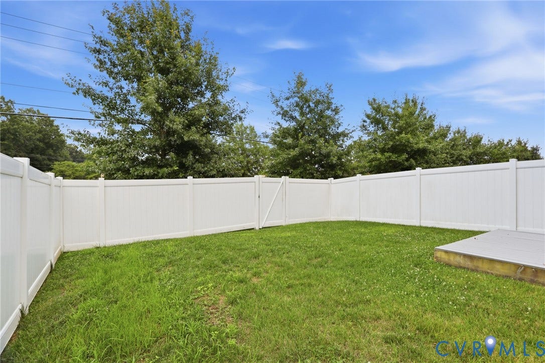 4101 New Hermitage Drive, Henrico, VA 23228 Fenced backyard featuring a white privacy fence, green lawn, and a small deck