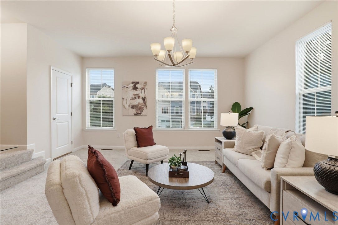 4101 New Hermitage Drive, Henrico, VA 23228 Spacious living area featuring carpet flooring, five windows with blinds, a white paneled door, and a multi-light chandelier