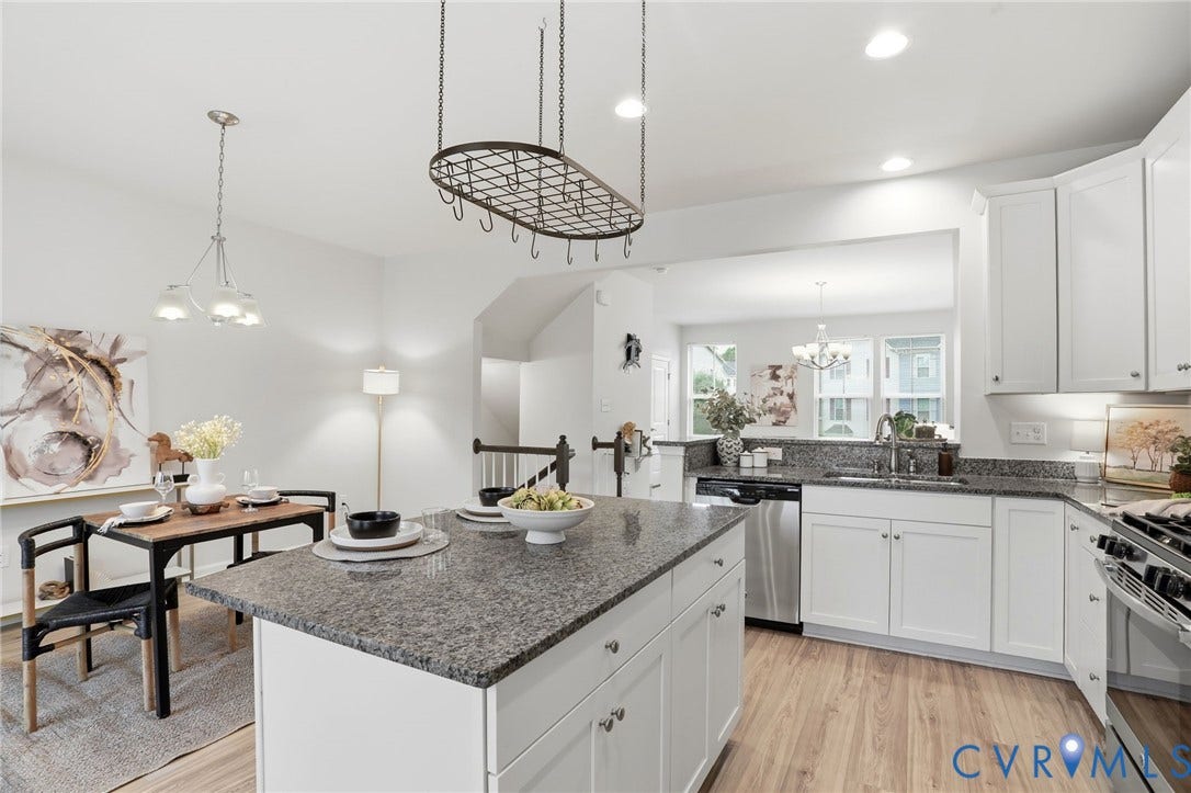 4101 New Hermitage Drive, Henrico, VA 23228 Open-concept kitchen and dining area featuring a central island with a granite-style countertop, white cabinetry, stainless steel appliances, and wood-finish flooring
