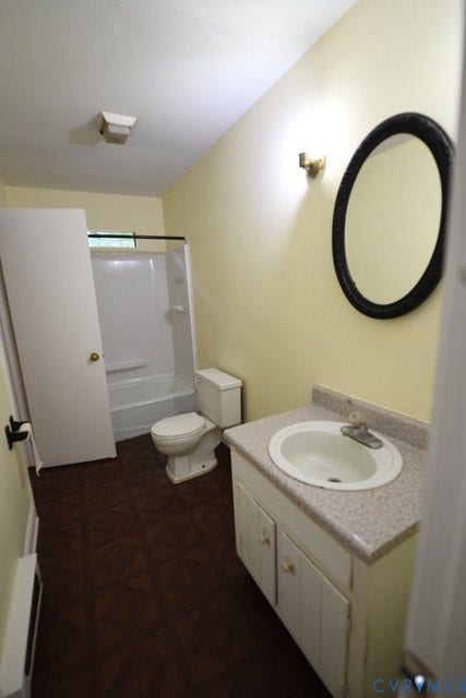 12720 Bailey Bridge Road, Bailey Bridge, Midlothian, VA 23112 Bathroom featuring a single vanity with a white basin sink, an oval mirror, a toilet, a full bathtub with shower/tub, and patterned dark flooring