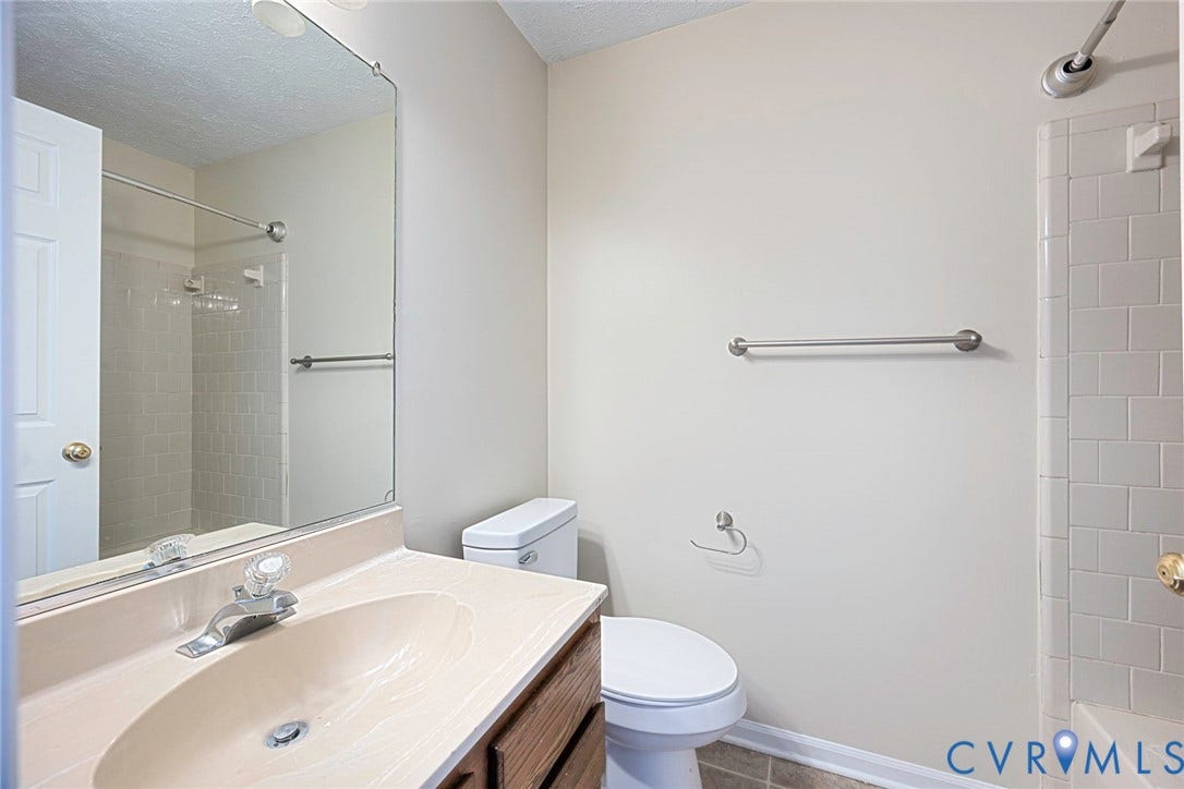 Neutral-toned bathroom featuring a vanity with an integrated sink and wood-finish cabinetry