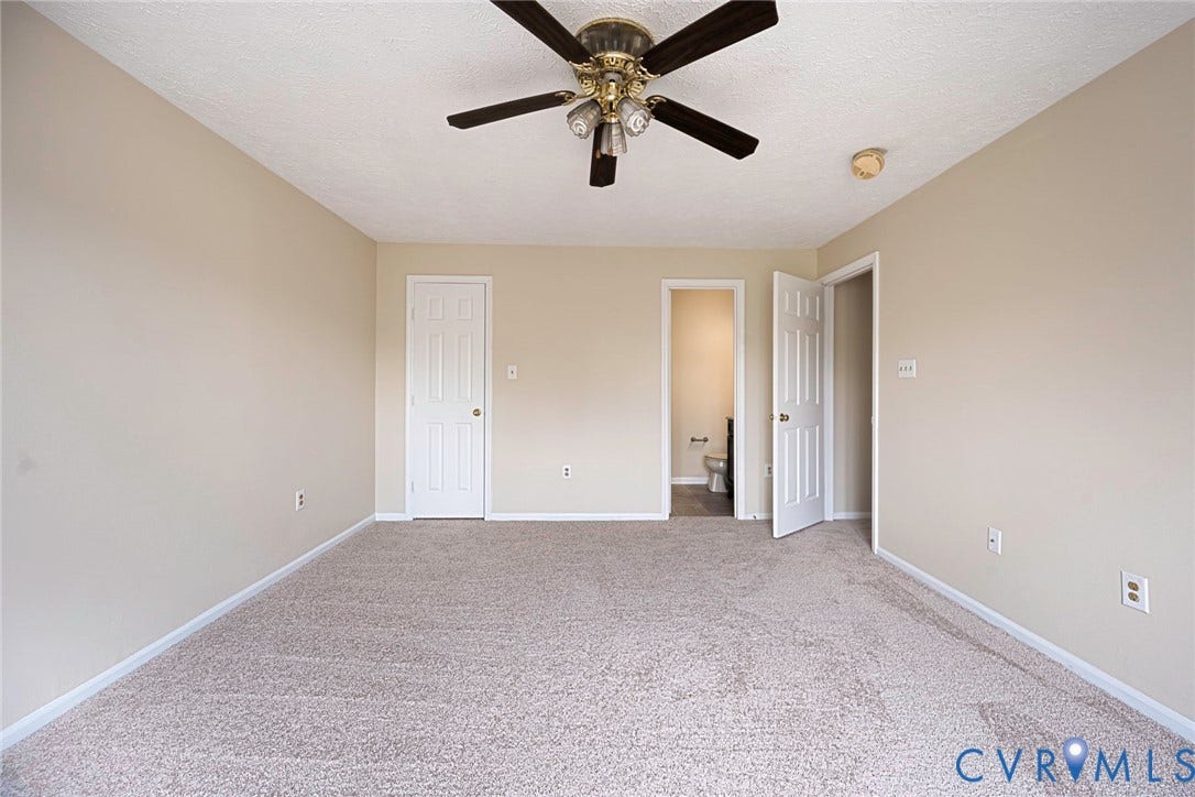 Carpeted room featuring a ceiling fan with light fixture, neutral wall paint, white baseboards, and two paneled interior doors
