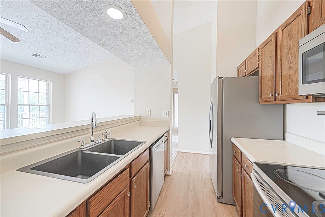 Kitchen featuring a dual basin sink, light-toned countertops, and wood-finish cabinetry