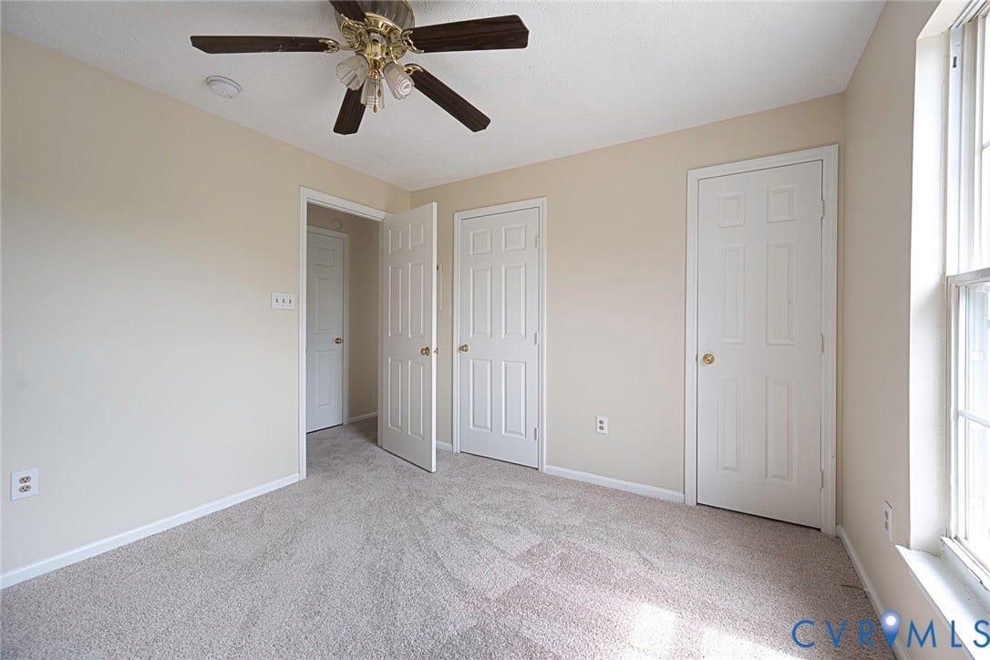 Carpeted room with neutral wall tones and a ceiling fan