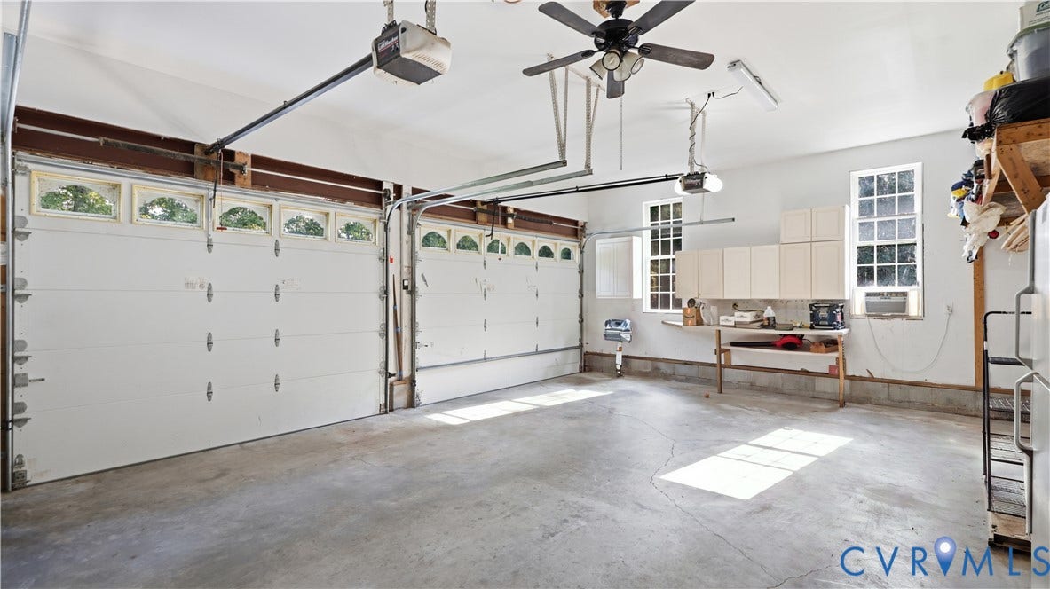 1836 Rocky Ford Road, Powhatan, VA 23139 Two-car garage featuring a concrete floor, two garage doors with arched windows, built-in cabinetry, and multiple windows