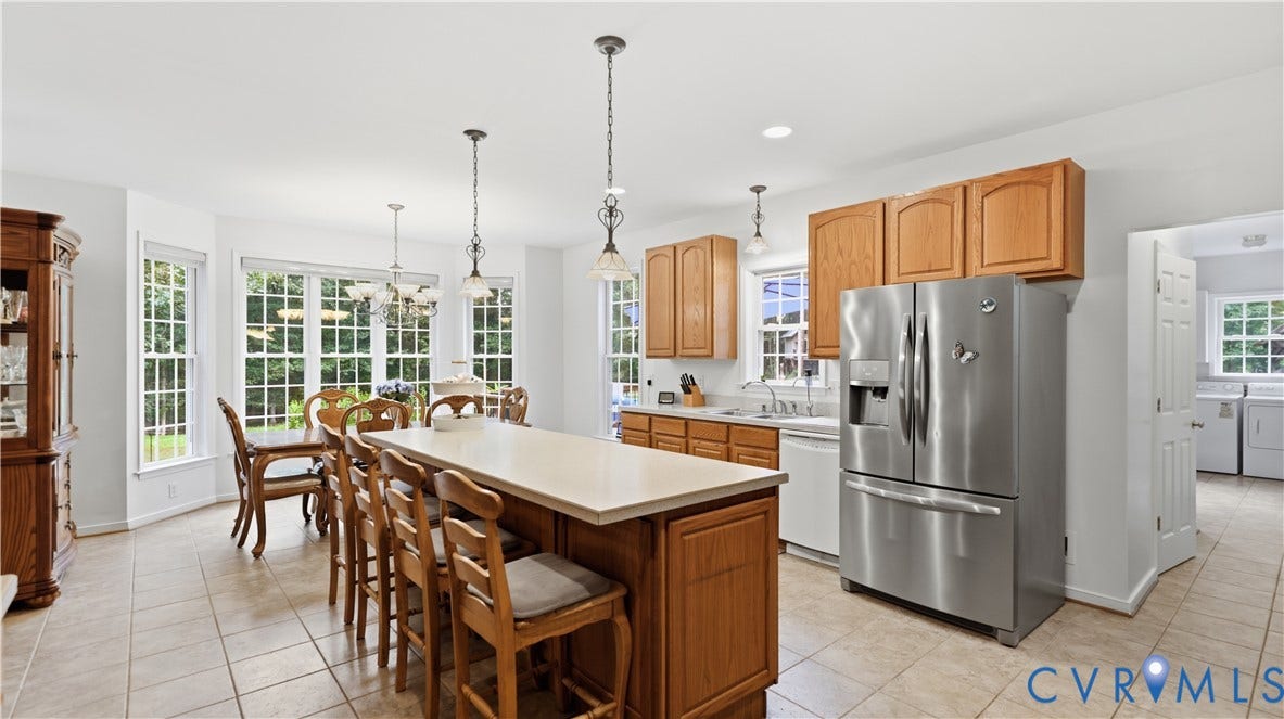 1836 Rocky Ford Road, Powhatan, VA 23139 Spacious kitchen featuring a central island with bar seating, pendant lighting, stainless steel refrigerator, wood cabinetry, and tiled flooring