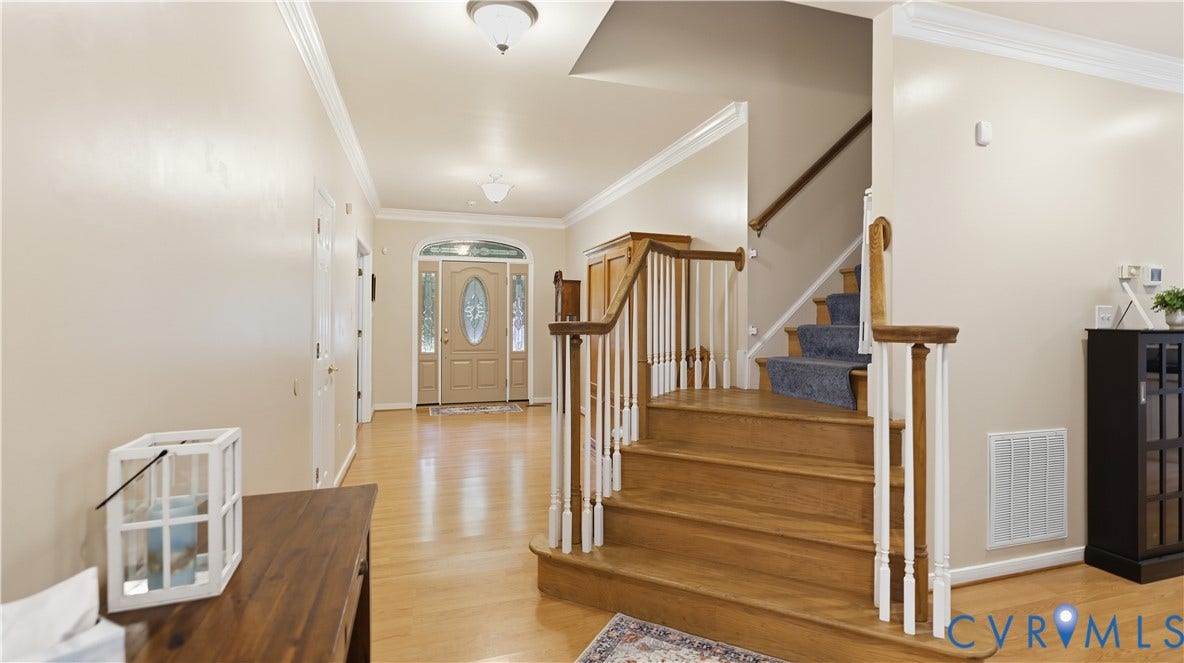 1836 Rocky Ford Road, Powhatan, VA 23139 Foyer featuring hardwood flooring, a wooden staircase with white spindles, a paneled front door with decorative glass inserts, and crown molding