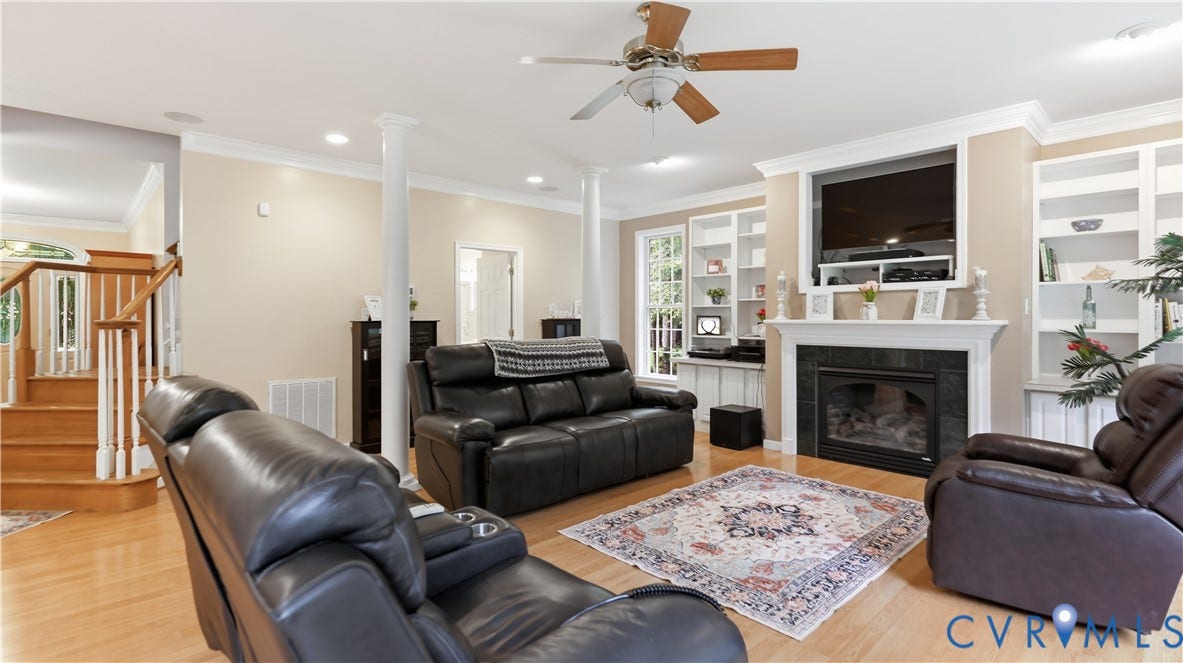 1836 Rocky Ford Road, Powhatan, VA 23139 Spacious living area featuring a fireplace with a white mantel and dark stone surround, built-in shelving, wood-finish flooring, and a ceiling fan