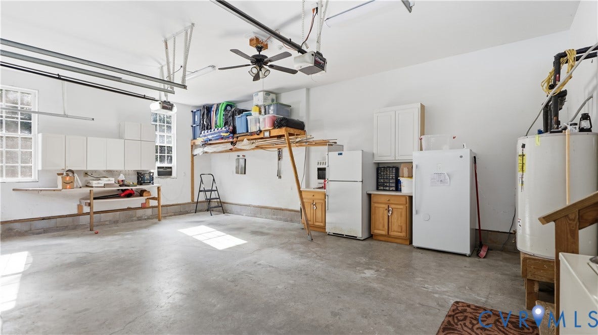 1836 Rocky Ford Road, Powhatan, VA 23139 Spacious garage featuring concrete flooring, multiple windows, a ceiling fan, built-in cabinetry, and a workbench area