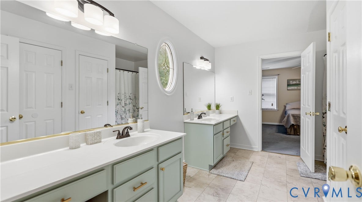 1836 Rocky Ford Road, Powhatan, VA 23139 Jack and Jill bathroom featuring dual vanities with light green cabinetry and white countertops, an oval window, and tiled flooring