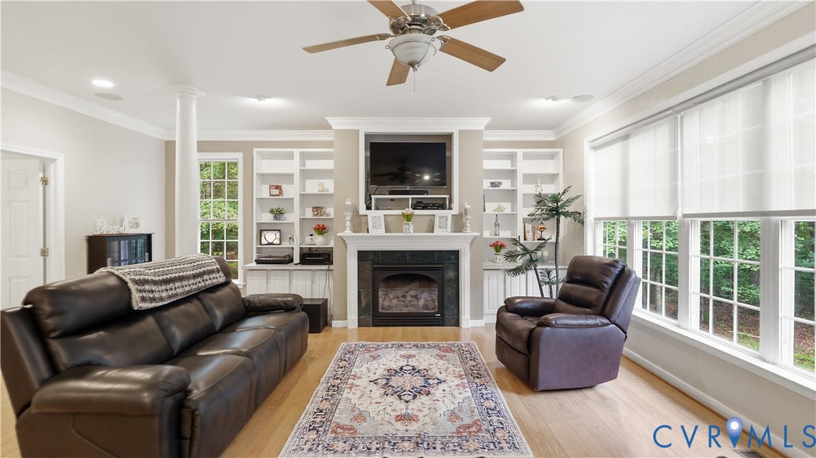 1836 Rocky Ford Road, Powhatan, VA 23139 Living room featuring a fireplace with a mantel, built-in shelving, wood-finish flooring, and crown molding