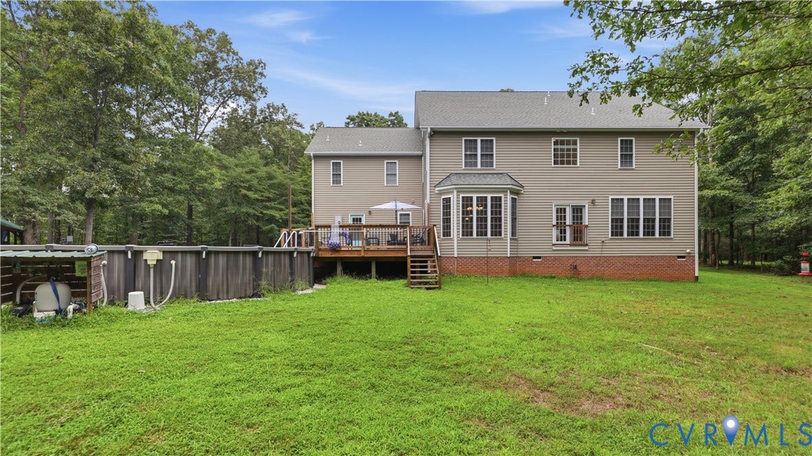1836 Rocky Ford Road, Powhatan, VA 23139 Rear exterior featuring a spacious wood deck, an above-ground swimming pool, and a bay window with multiple panes